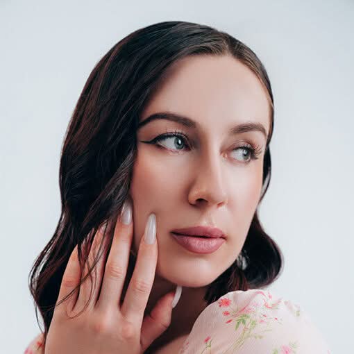 Close-up portrait of a woman with braided hair touching her face and looking thoughtfully to the side