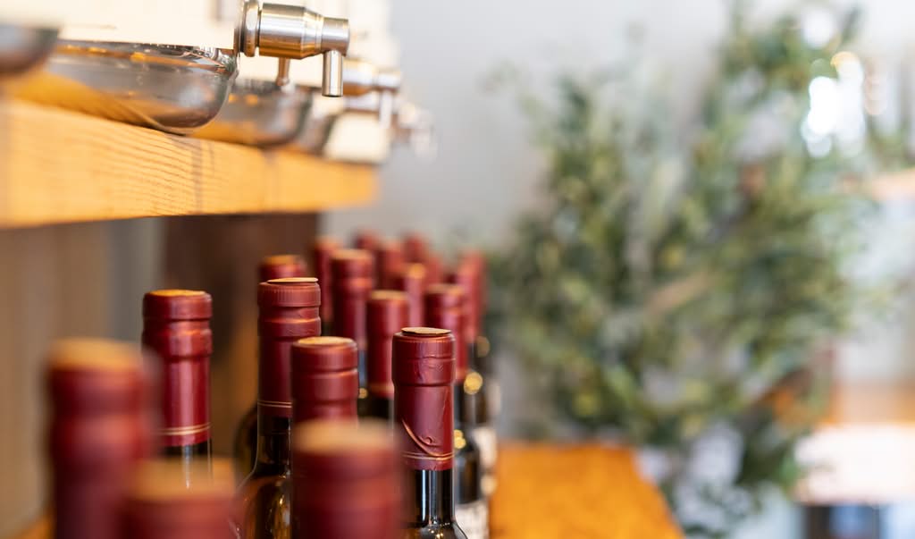 Olive oil bottles arranged upright in a warm commercial interior with controlled product lighting.